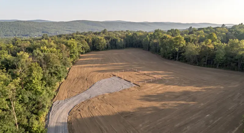Graded building pad with survey stakes and gravel driveway
